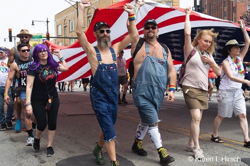 Large American flag held up by marchers in dungarees